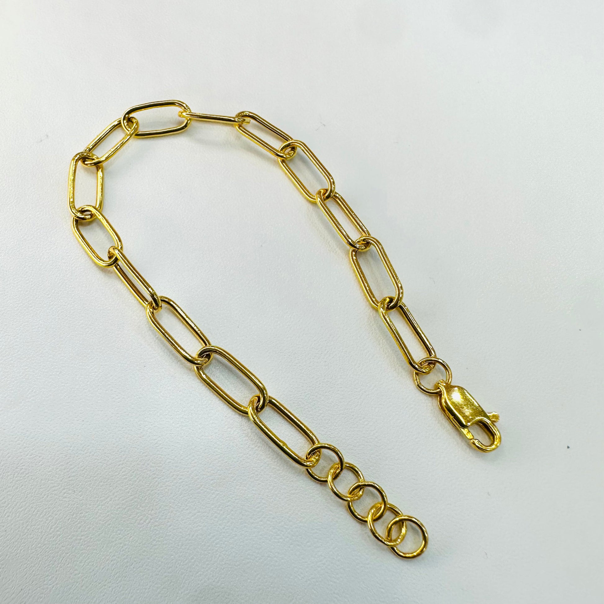 Gold chain bracelet on a light gray background