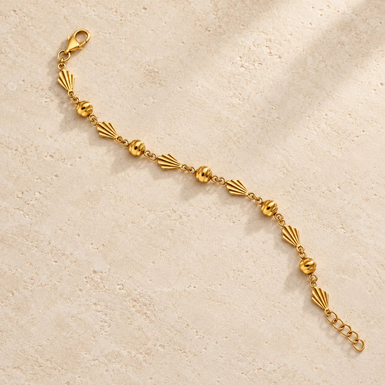 Guild Bullion gold bracelet with shell and bead details on warm ivory stone