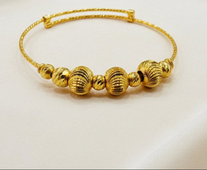 916 gold baby bangle with textured beads on a neutral display