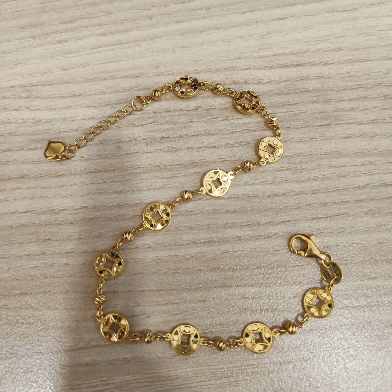 Adjustable 916 gold round motif bracelet laid open