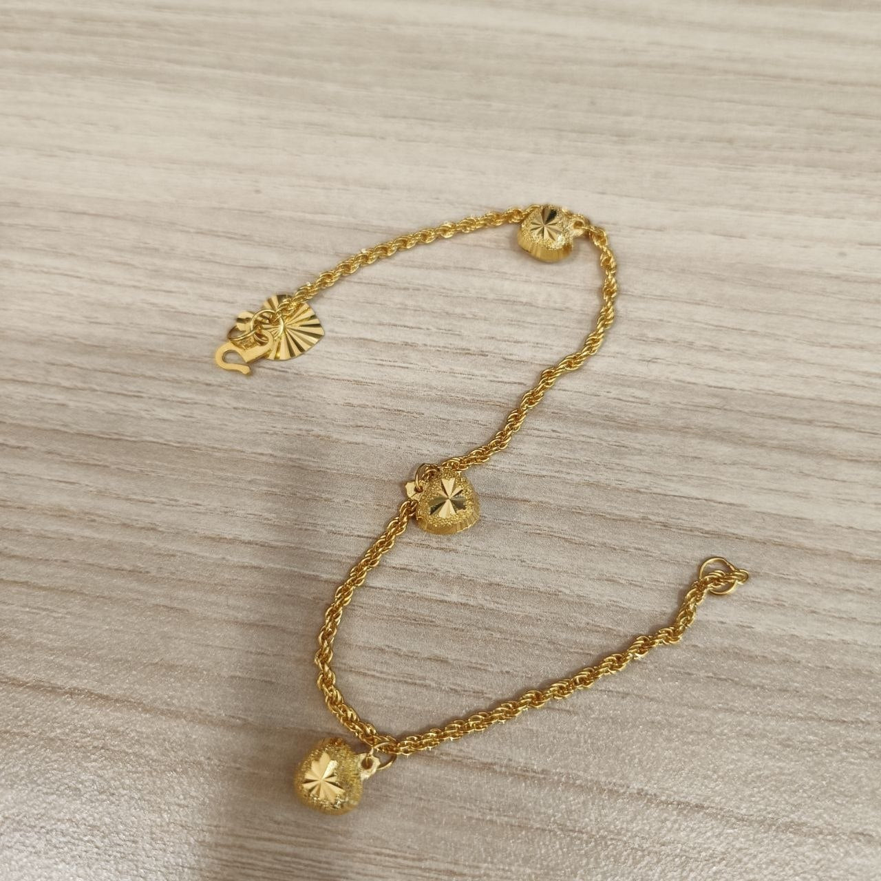 916 Gold hollow rope bracelet with dangling heart charms laid flat