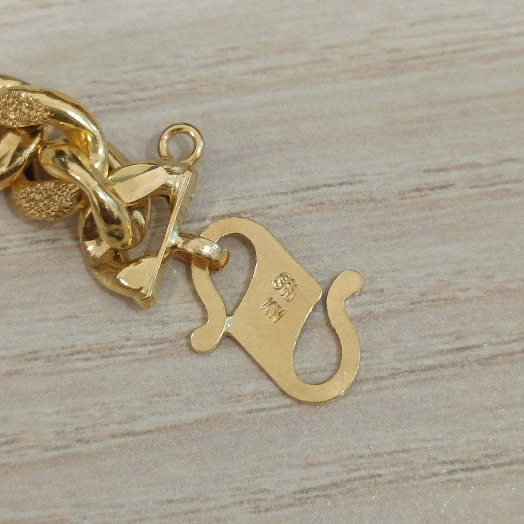 Close-up of the Cowboy-link gold bracelet end fitting and attached gold tag