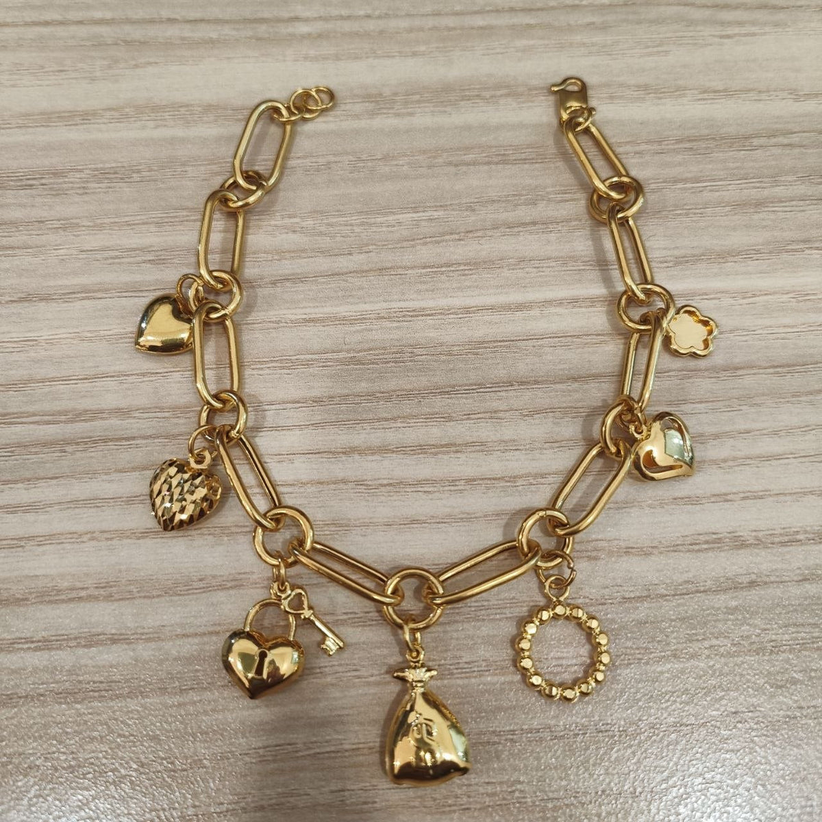 916 gold anchor bracelet with assorted charms laid flat, BR26765