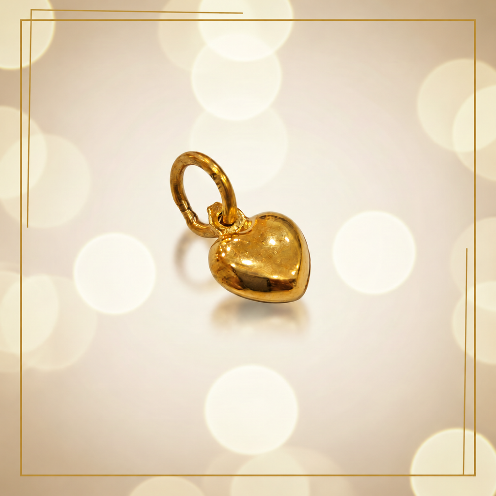 Polished 916 gold heart pendant with an oval gold loop on a cream bokeh background