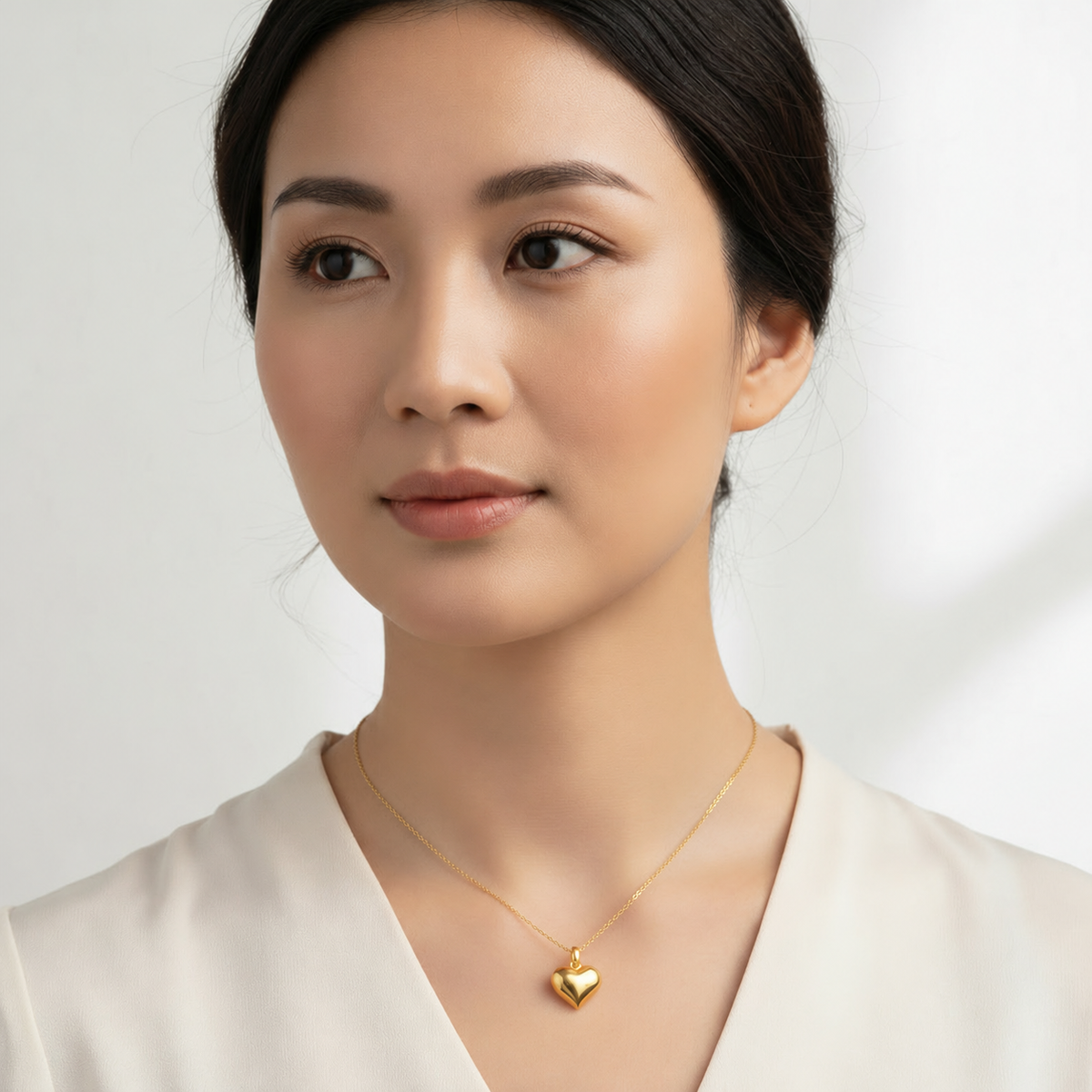 Model wearing a polished 916 gold heart pendant on a fine chain