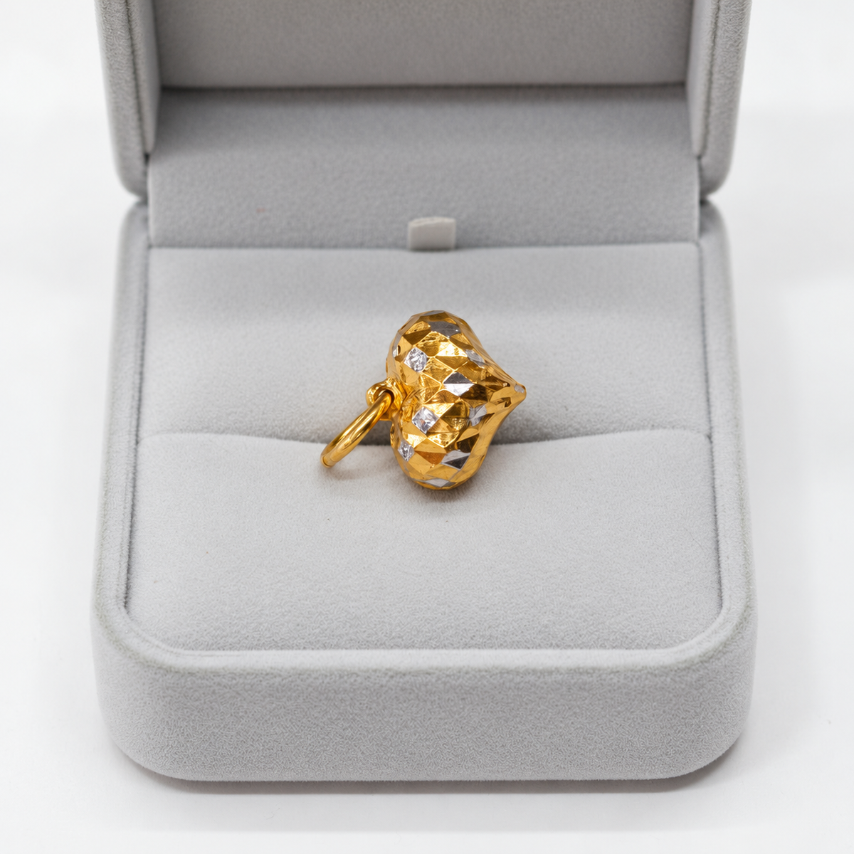 Faceted two-tone 916 gold heart pendant resting in a grey jewellery box