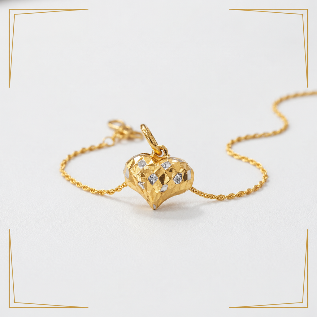 Faceted two-tone 916 gold heart pendant styled beside a gold chain on white