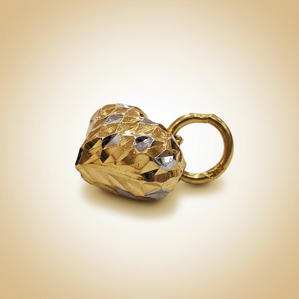 Side view of a faceted two-tone 916 gold heart pendant with its gold loop on a cream background