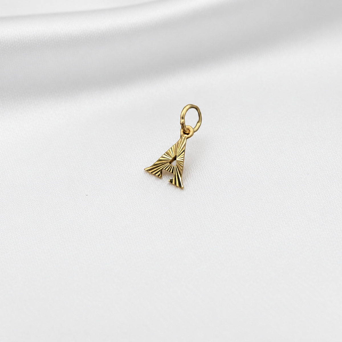 Guild Bullion 916 gold letter A pendant with radiating cut detail on white satin
