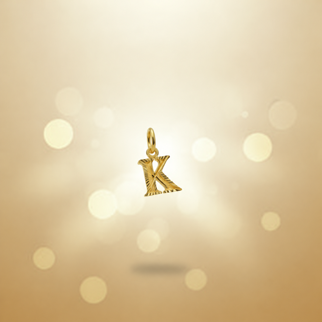 Guild Bullion 916 gold letter K pendant with cut edges on a warm gold background