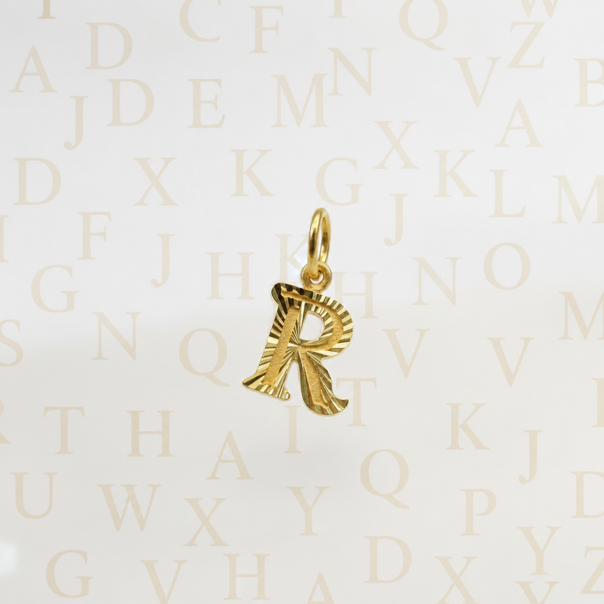 Guild Bullion 916 gold letter R pendant with hanging loop on an alphabet background