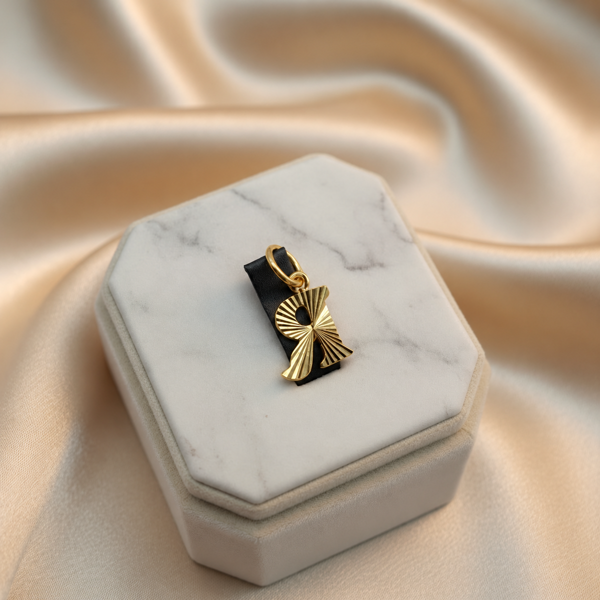 Guild Bullion 916 gold letter R pendant in reverse orientation on a marble jewellery display