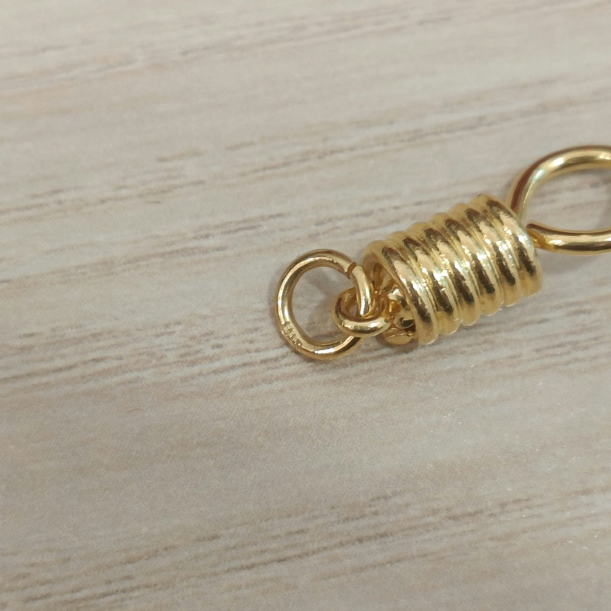 Close-up of connecting ring and ridged centre on 916 gold amulet hook PD30087