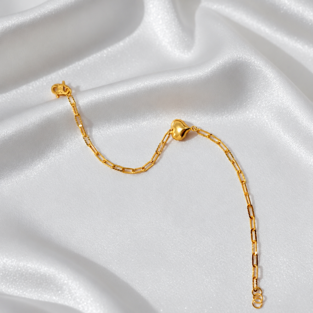 Curved view of BR24467 22K gold Clip-Link Heart Bracelet showing polished heart and end rings on white satin
