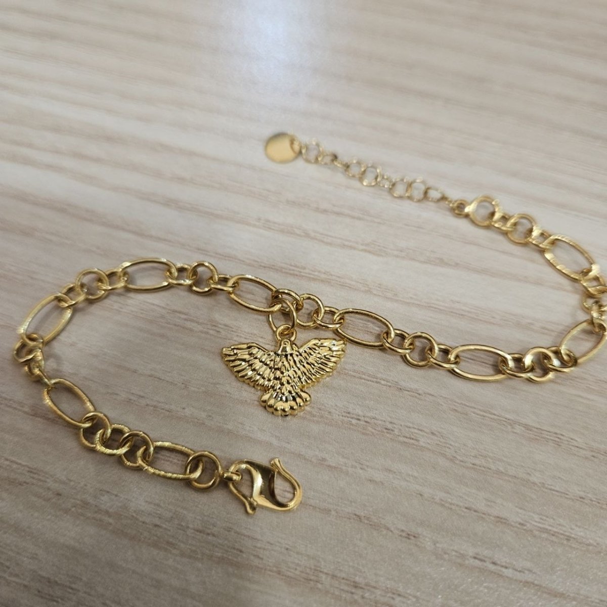 Full arrangement of the 916 gold spread-wing bird charm bracelet with extension chain and lobster clasp