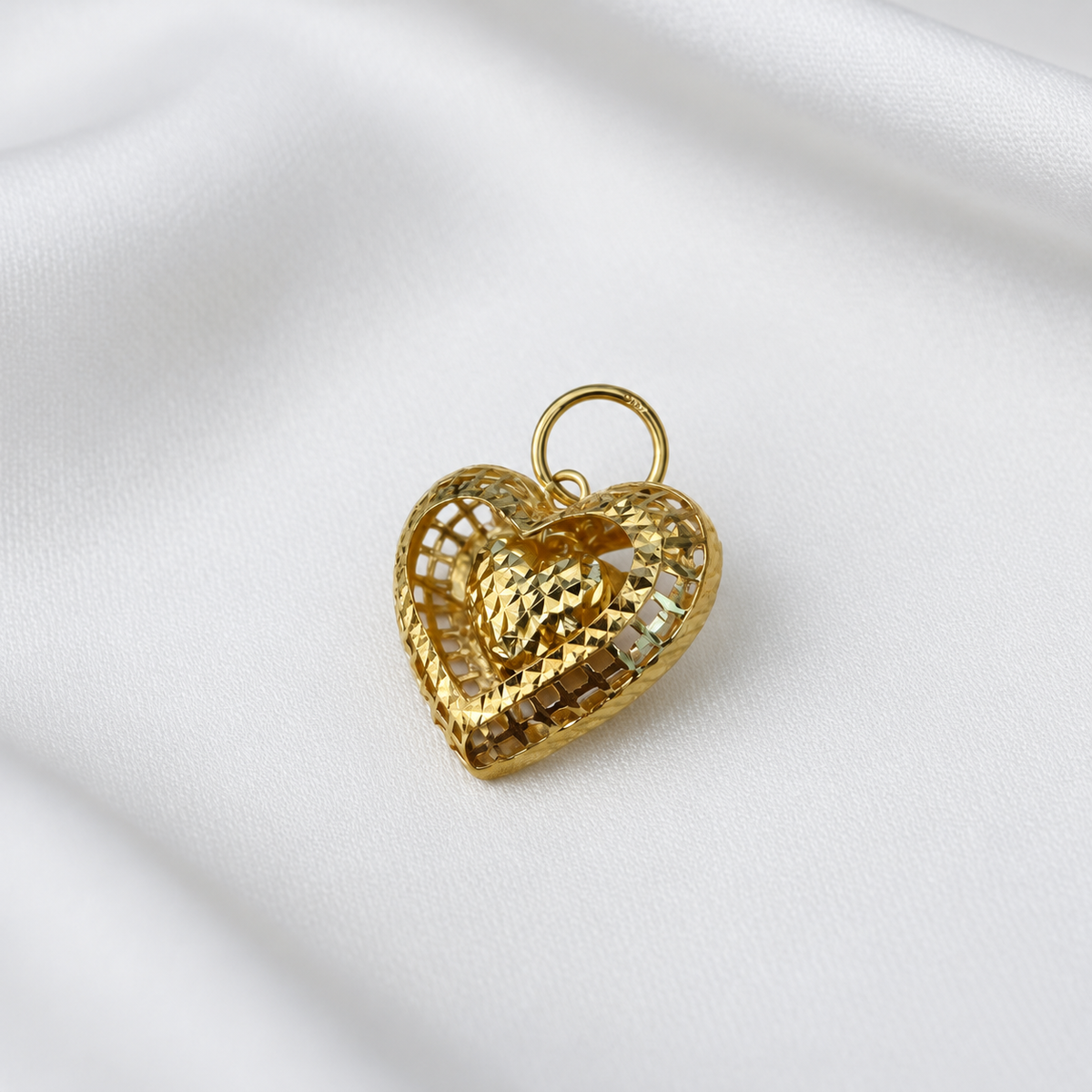 916 gold open heart pendant with a dangling faceted heart centre and round gold loop on white satin