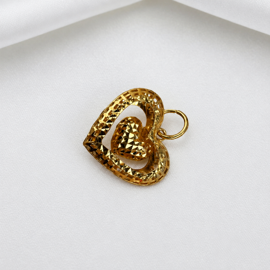 Diagonal view of the 916 gold open heart frame and dangling faceted heart pendant on white satin