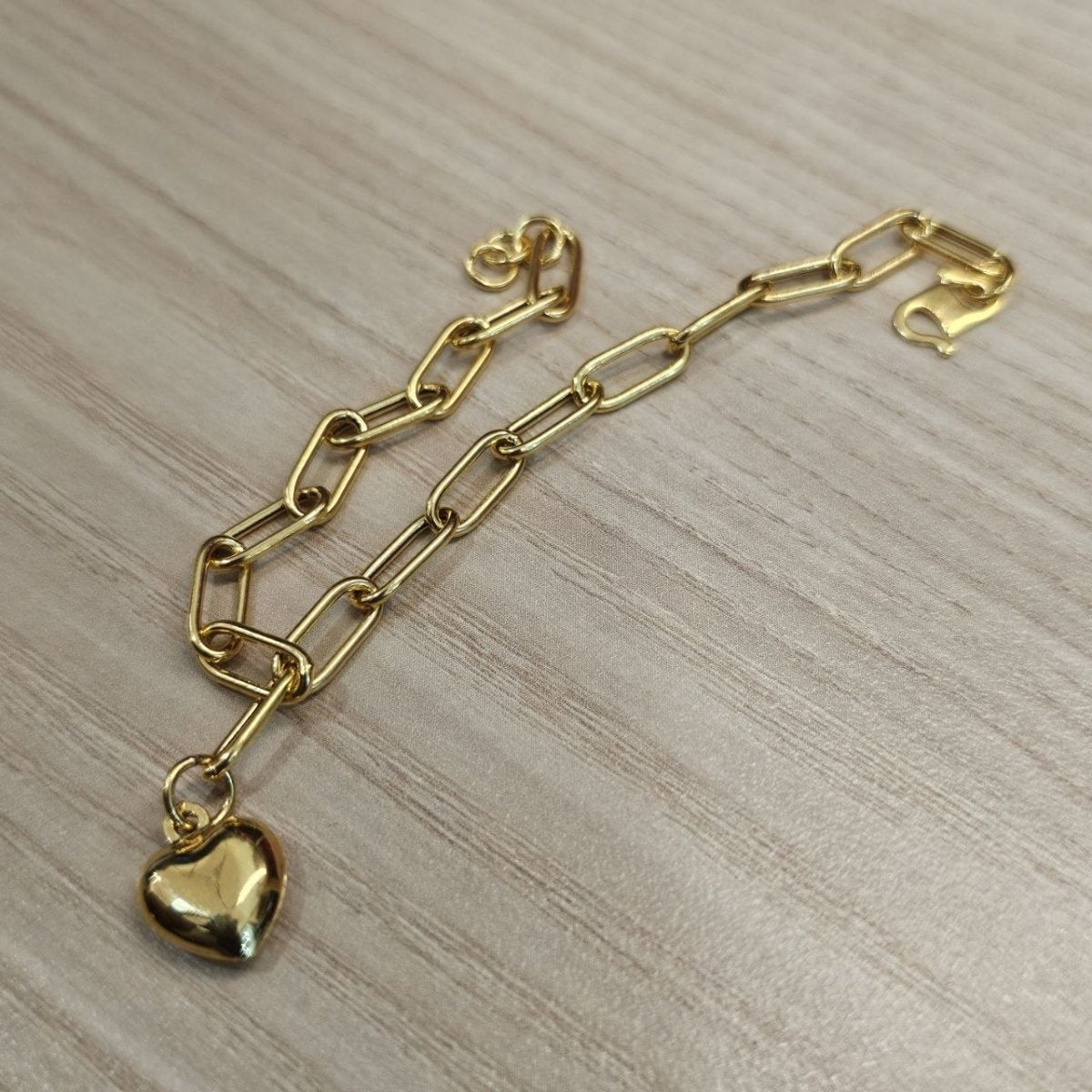 916 gold Dangling Heart Bracelet V2 BR25204 with heart charm in the foreground on wood