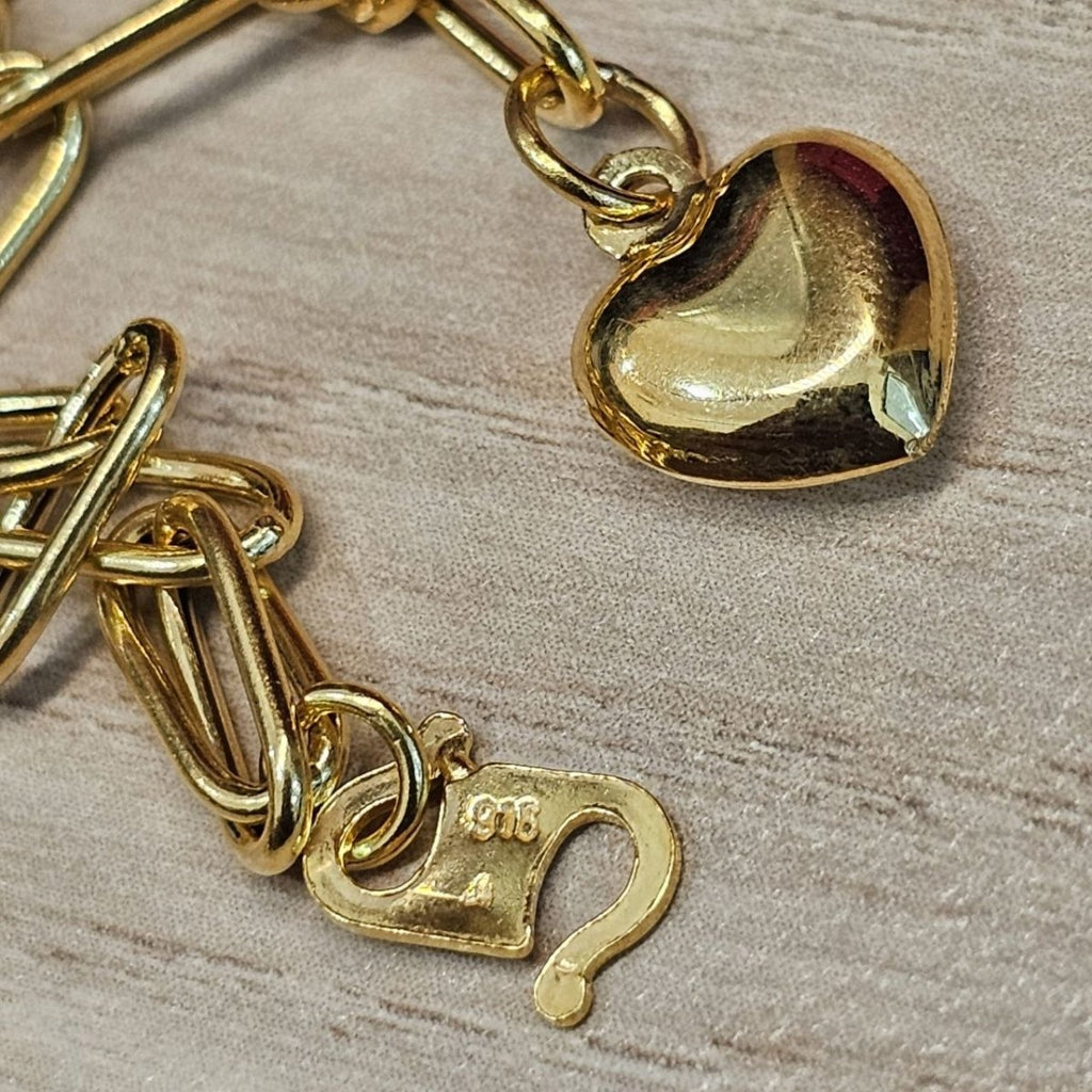 Close-up of heart charm and 916 stamp on the hook clasp of gold bracelet BR25206