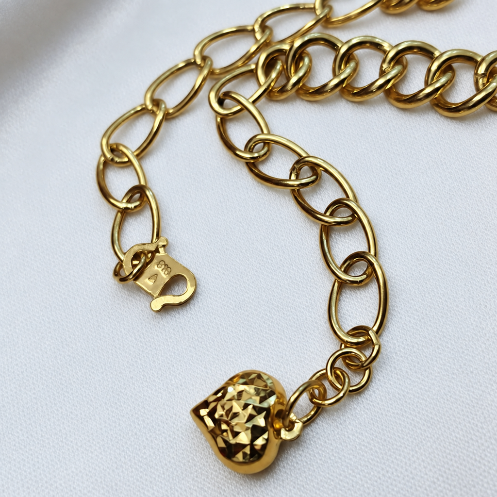 Close-up of oval links, hook clasp and faceted heart charm on the 916 gold dual design bracelet