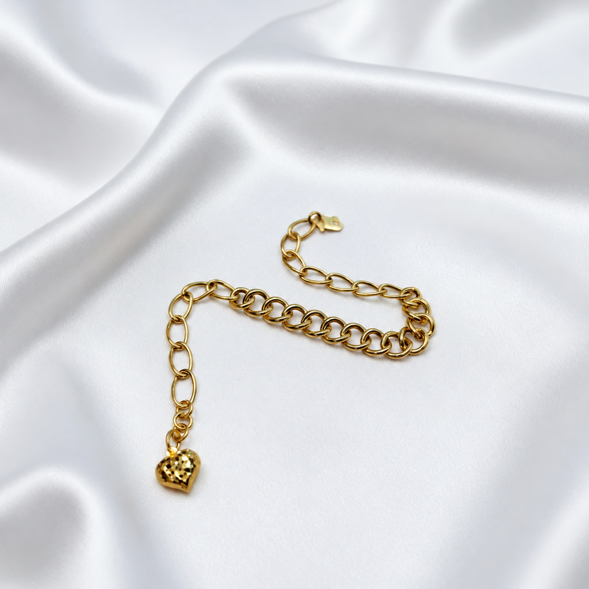 916 gold dual design link bracelet with heart charm arranged in an S curve on satin