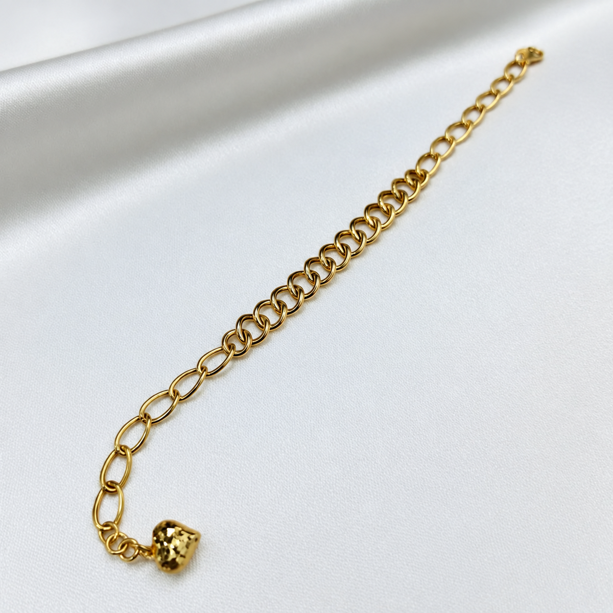 916 gold dual design link bracelet with heart charm extended diagonally on white satin