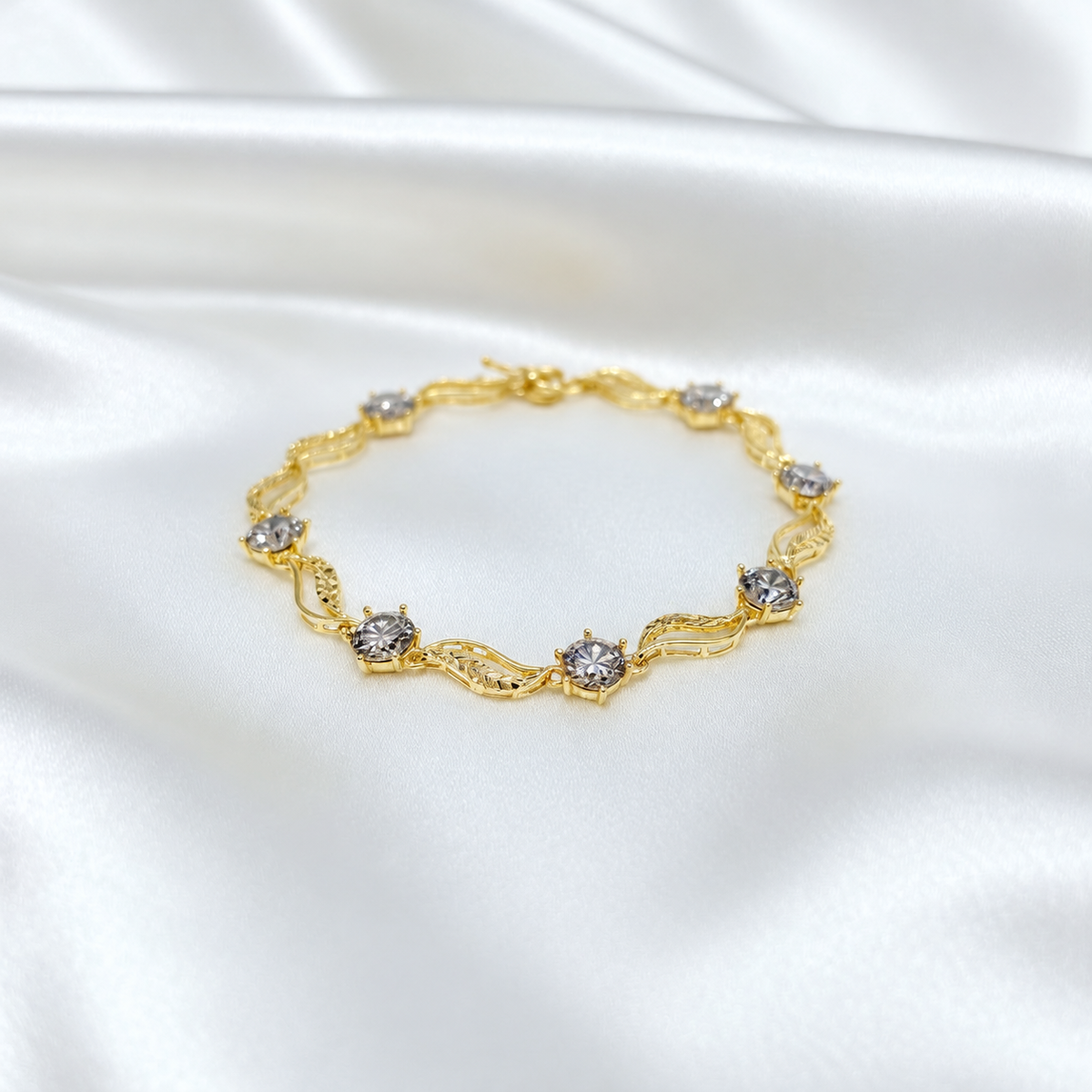Reference leaf-link bracelet arranged in a circle on white satin with round silver-coloured accents