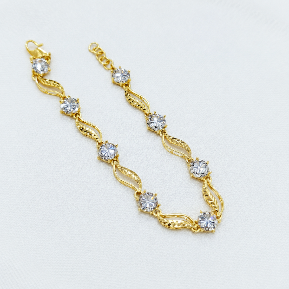 Reference leaf-link bracelet extended on white fabric with hook clasp and adjustment rings