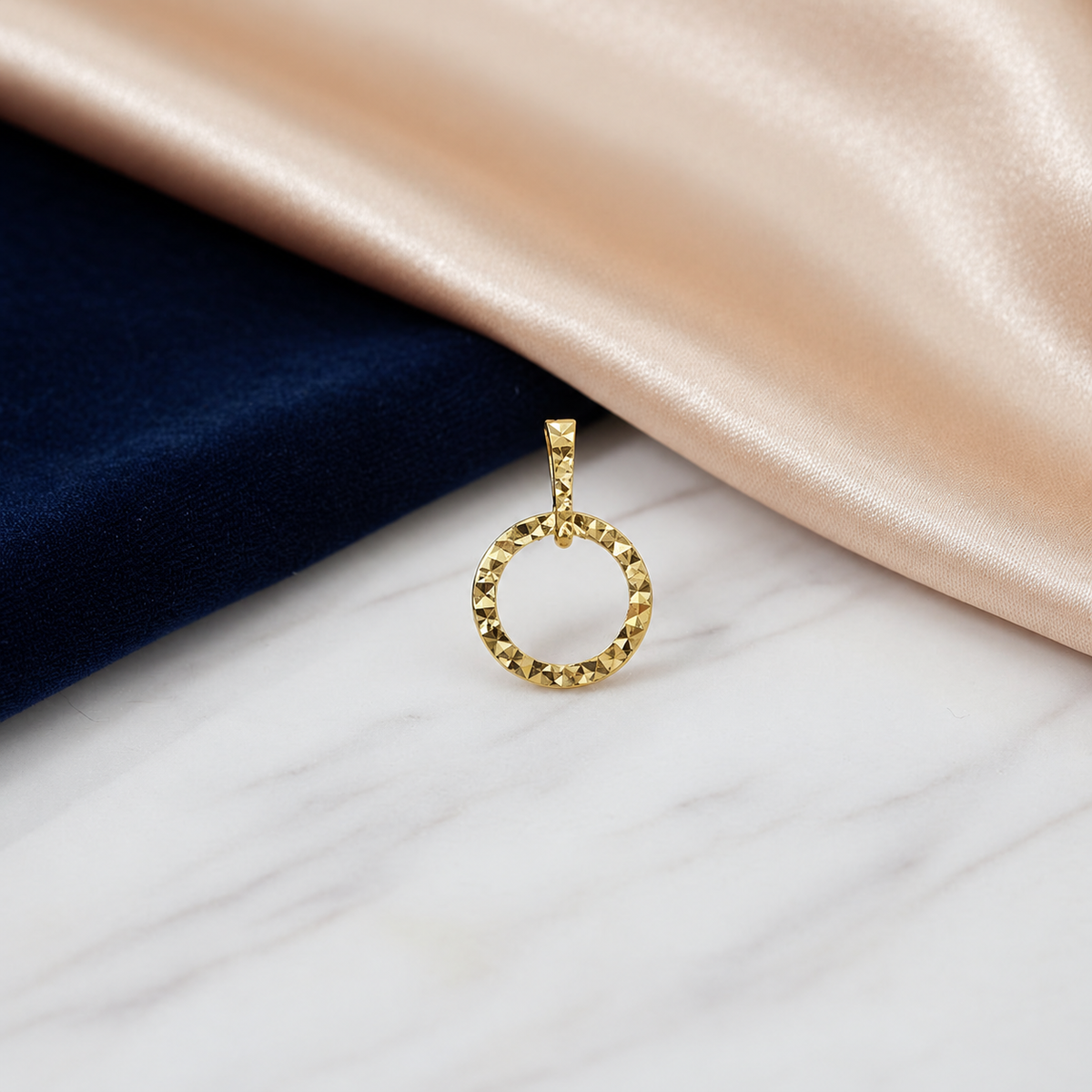 Reference circle design in 916 gold with a faceted rim and bail on marble