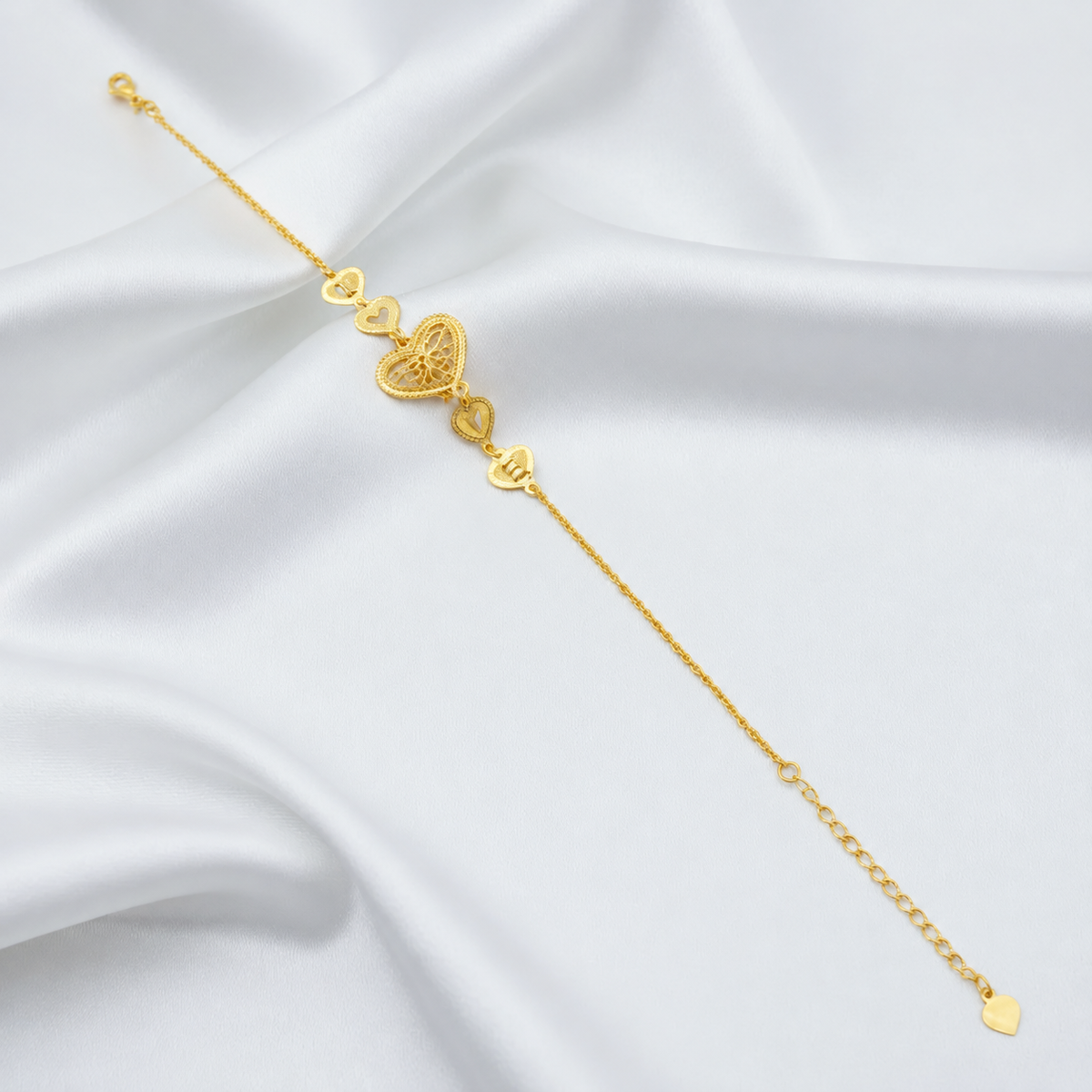 BR20620 916 gold Golden Heart Chain Bracelet extended on white satin with filigree heart, four small heart links and extension chain
