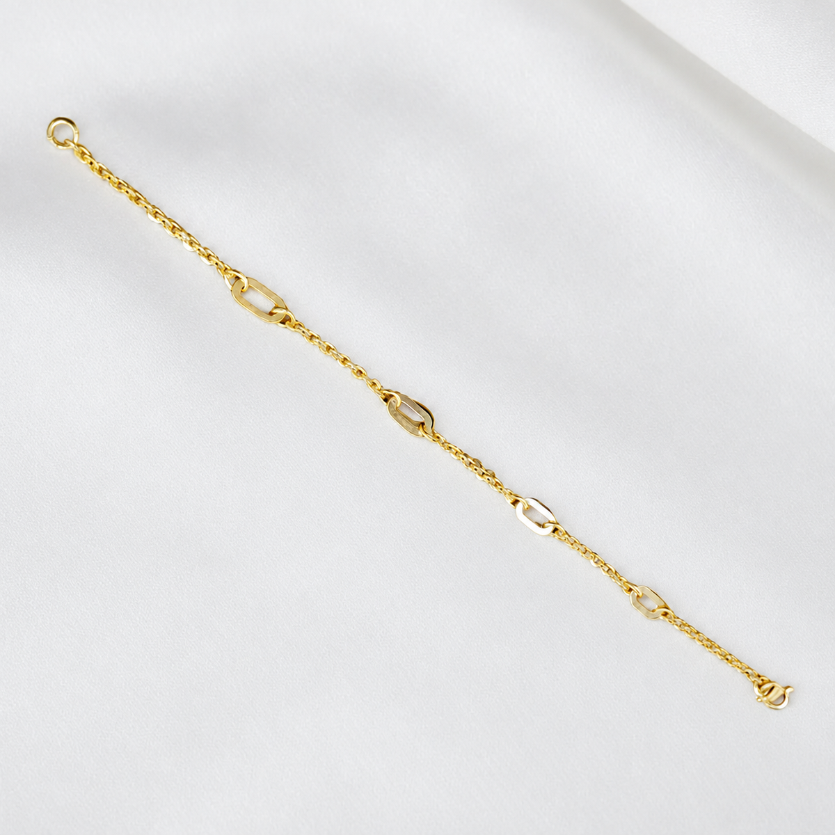 Full length view of the 916 gold Golden Link Charm Bracelet with connecting rings and lobster clasp on white satin