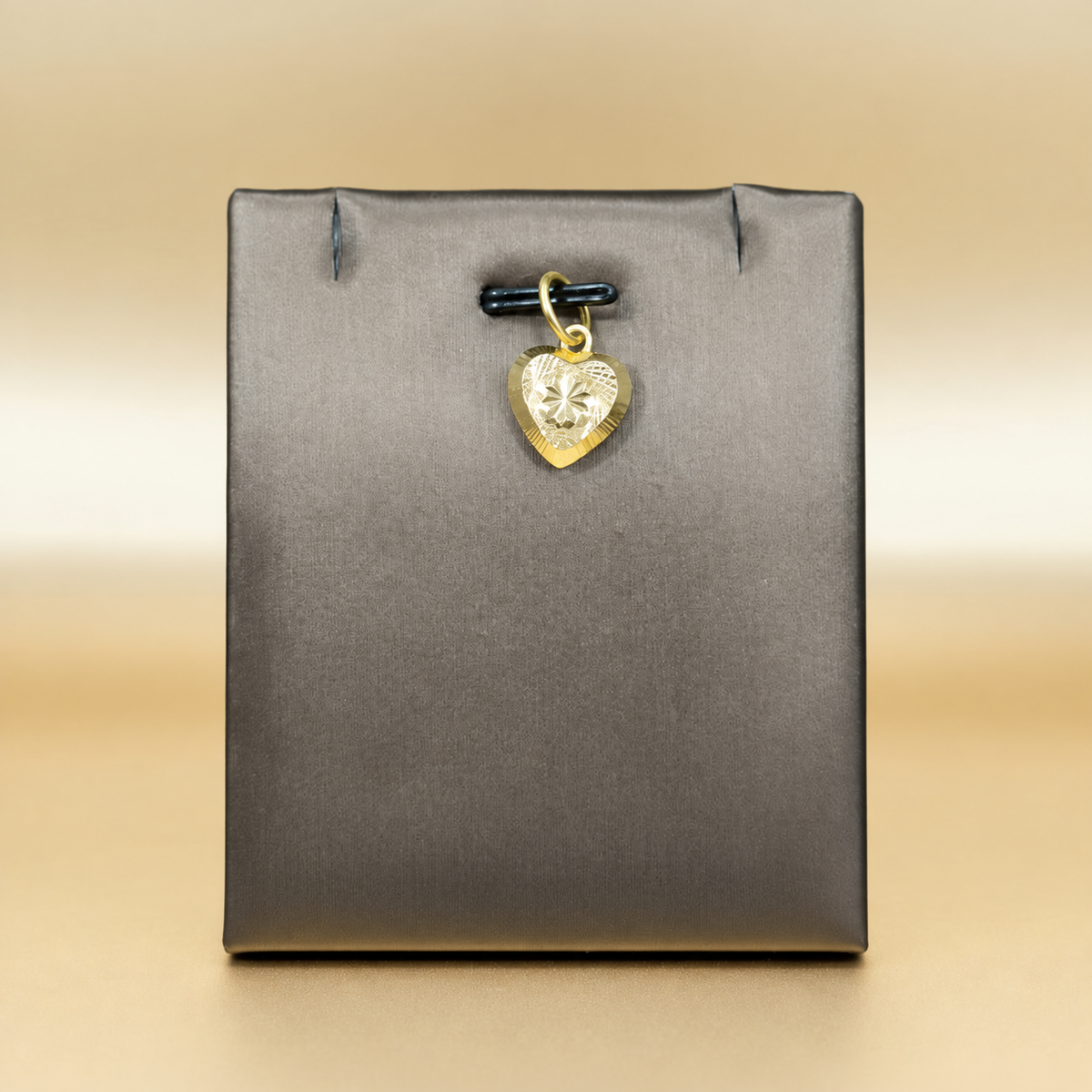 Reference view of a patterned star-centre 916 gold heart pendant on a grey display