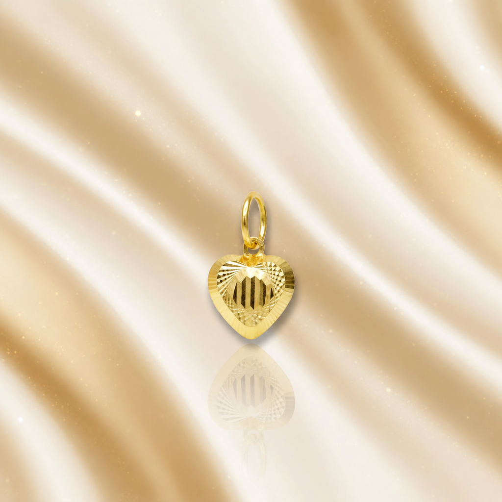 Reference view of a striped-centre 916 gold heart pendant with reflection on cream