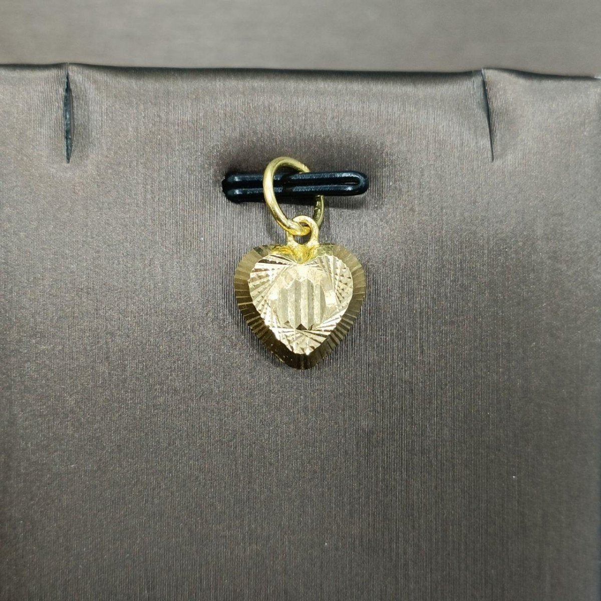 Reference close-up of a striped-centre 916 gold heart pendant on a grey jewellery display
