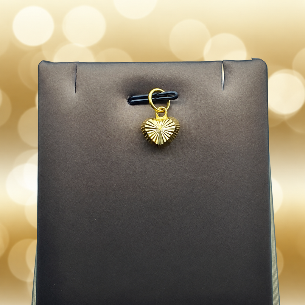 Reference view of a radiating-cut 916 gold heart pendant on a grey display
