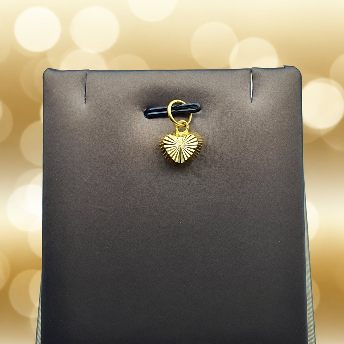 Reference view of a radiating-cut 916 gold heart pendant on a grey display