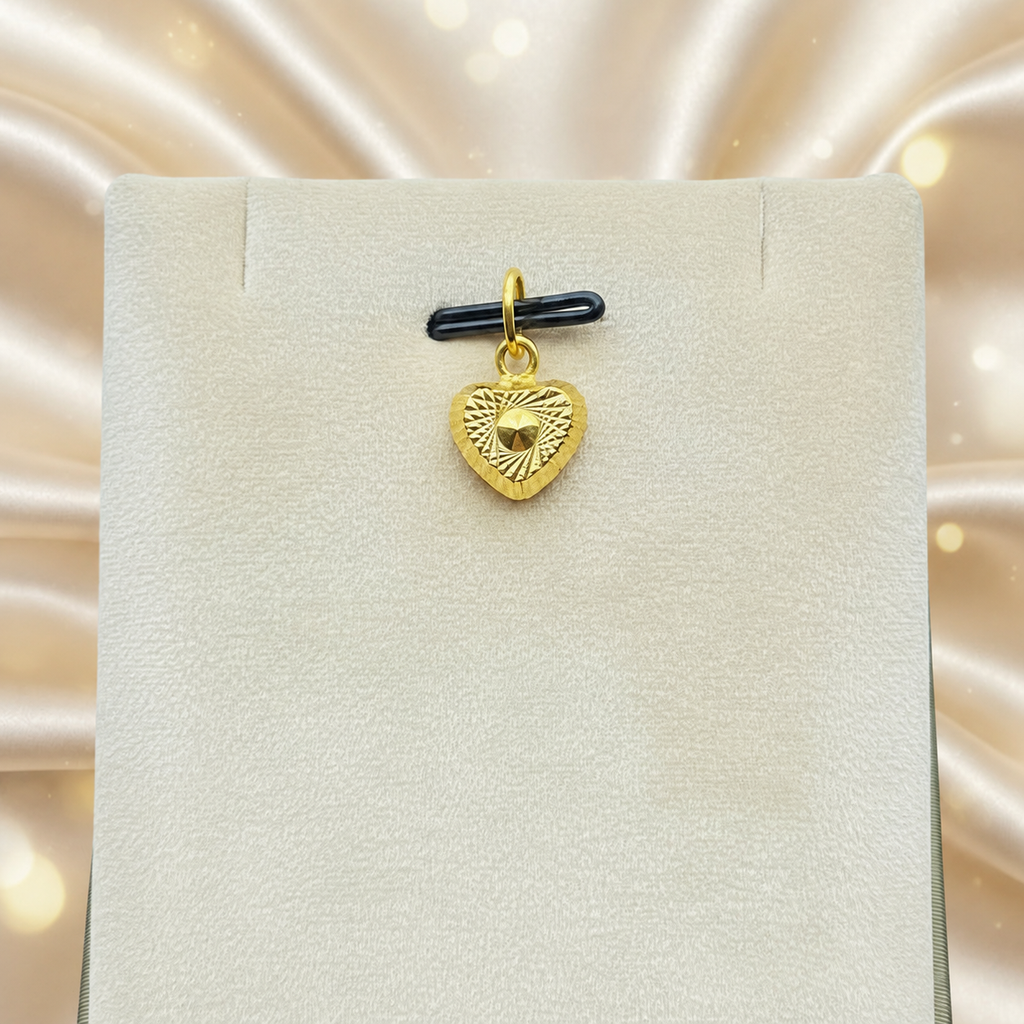 Reference view of a patterned 916 gold heart pendant on a cream jewellery display