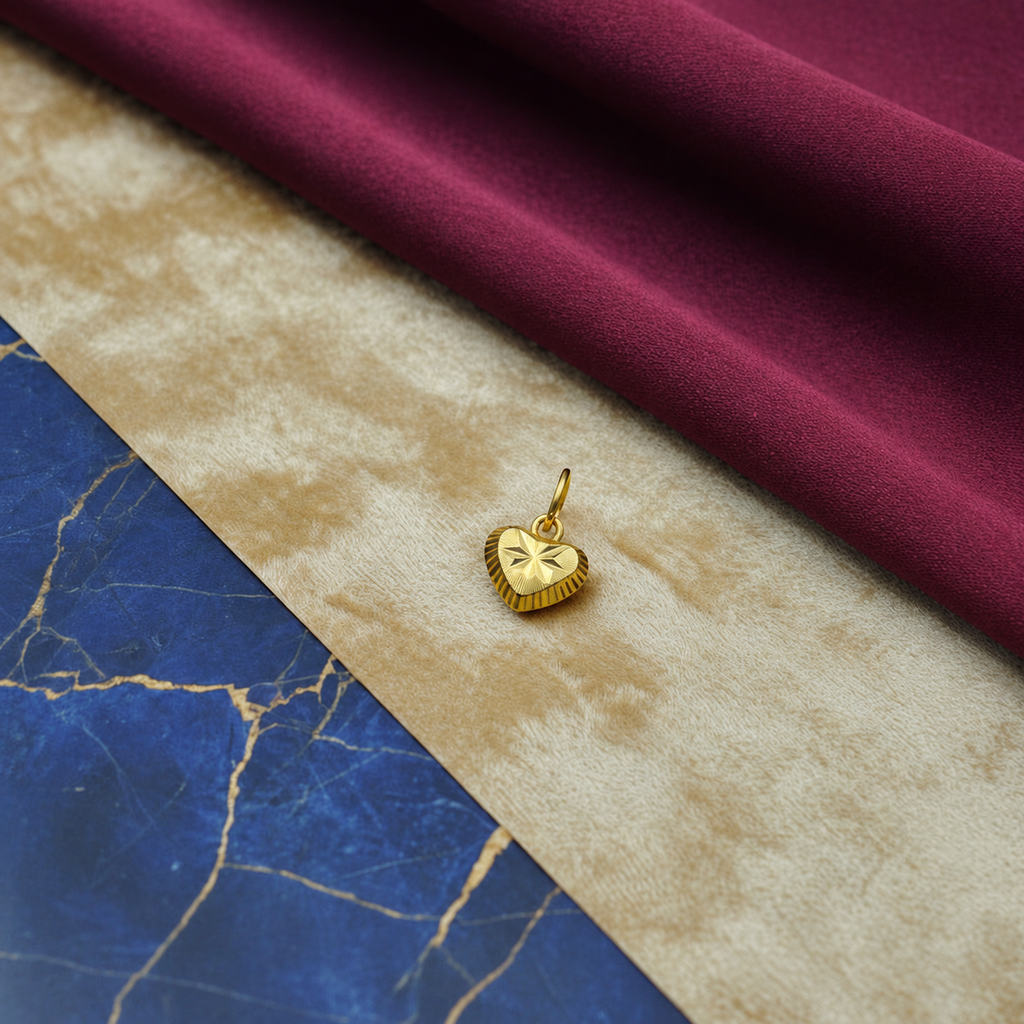 Star-centre 916 gold heart pendant on a cream surface beside burgundy cloth and blue marble