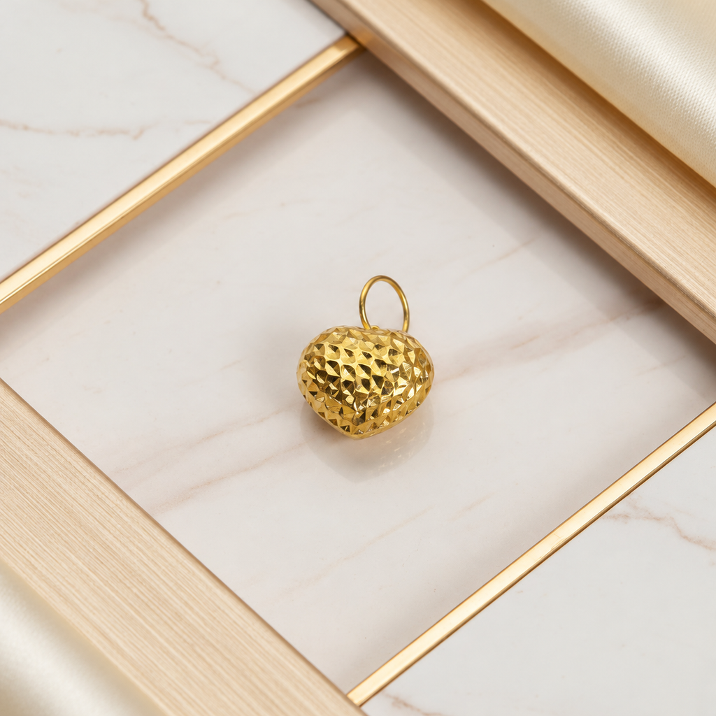 Yellow-gold 916 large faceted heart pendant with an upright gold loop on framed pale marble