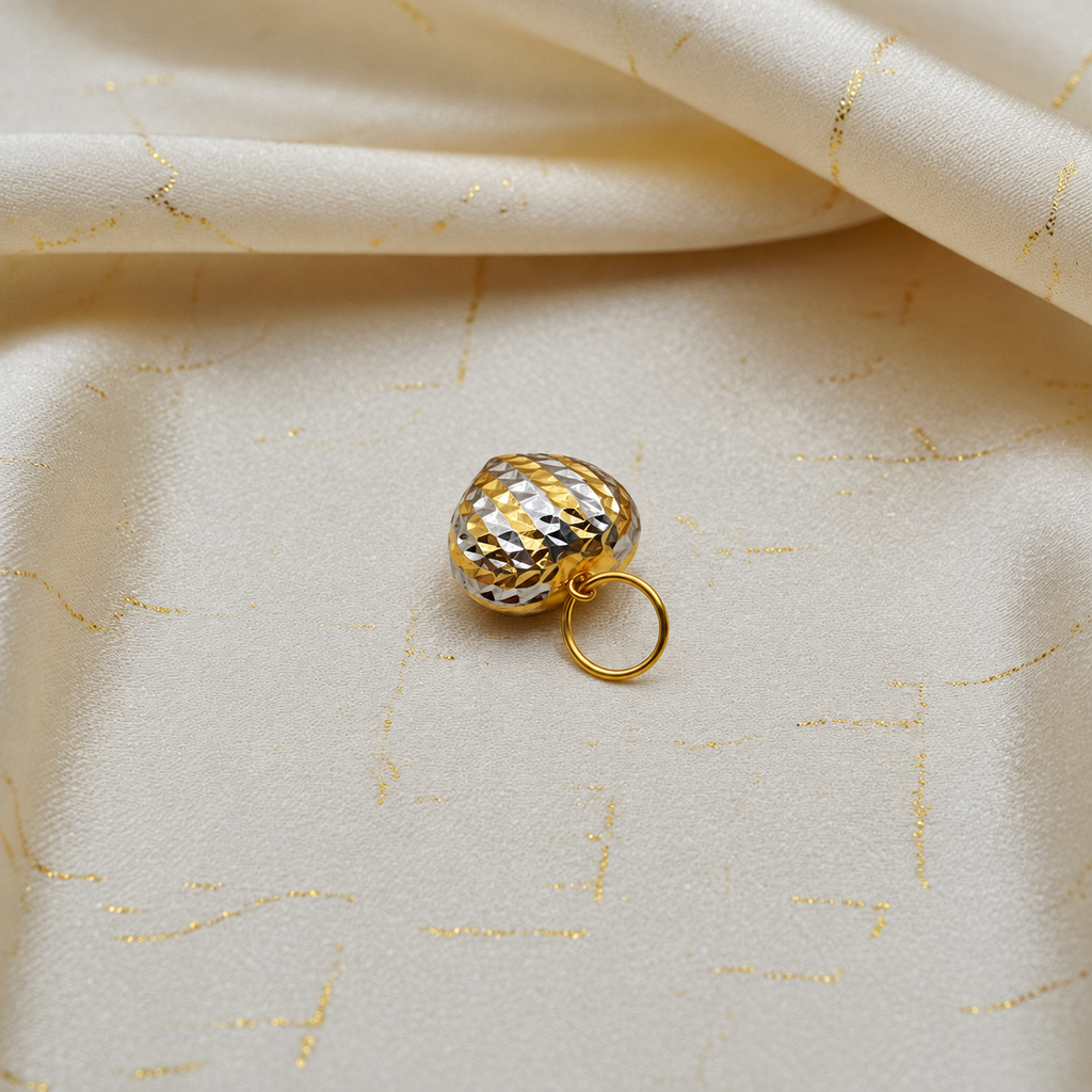 Two-tone 916 large faceted heart pendant resting on cream satin with gold stitching