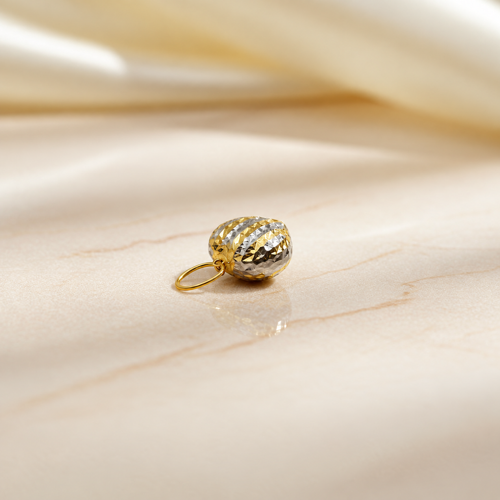 Side view of a two-tone 916 faceted heart pendant on pale marble