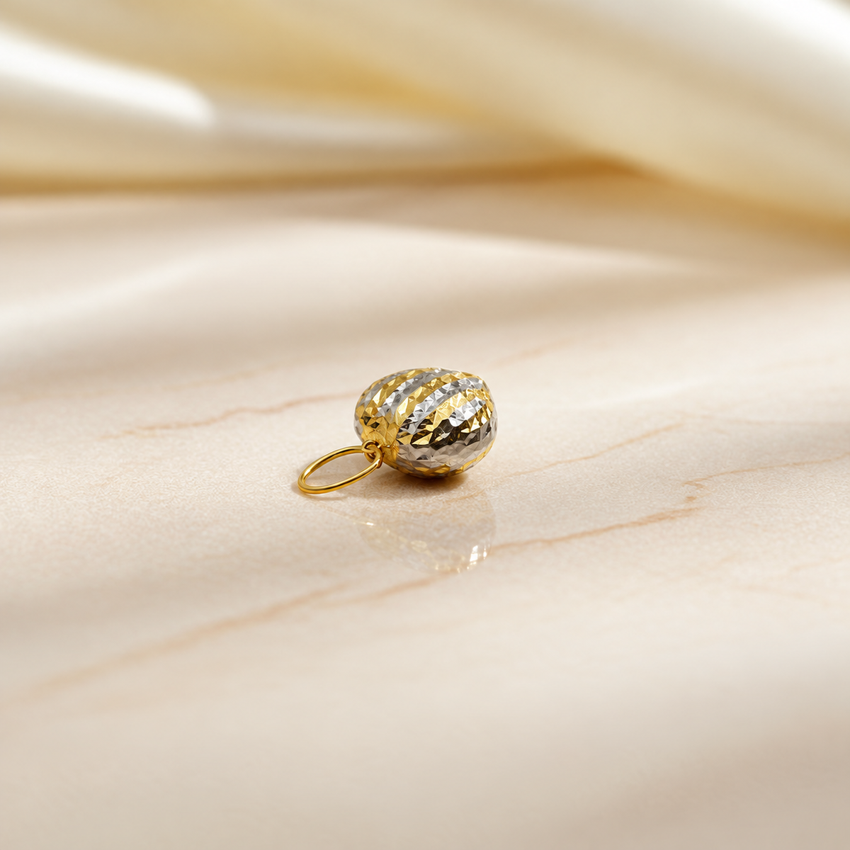 Side view of a two-tone 916 faceted heart pendant on pale marble