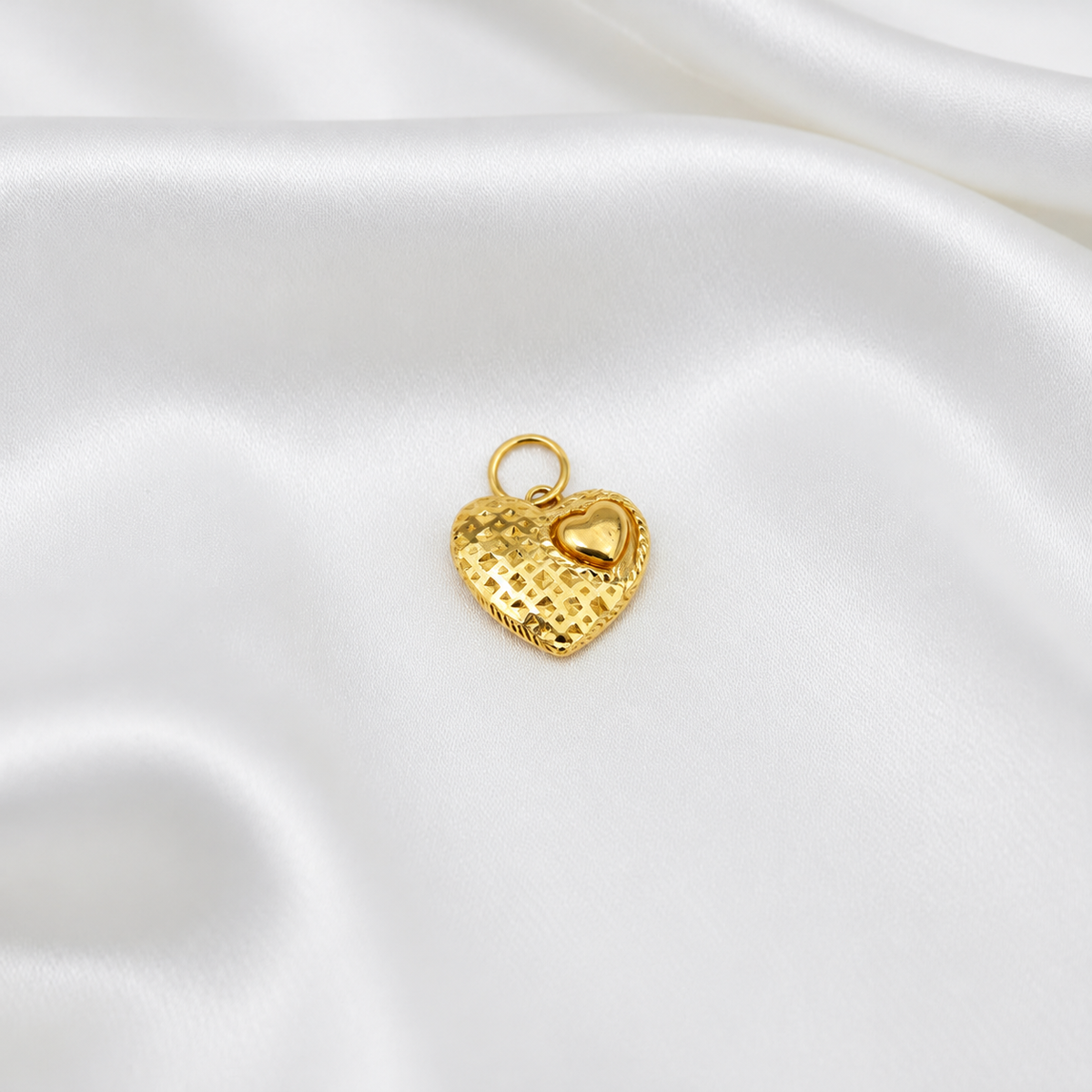 Straight front view of the 916 gold mini-heart accent pendant on white satin