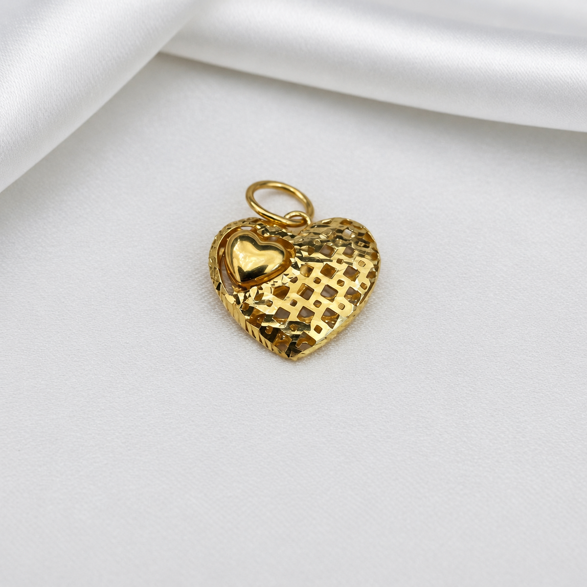 Close-up of the 916 gold heart pendant showing grid texture and polished mini-heart detail