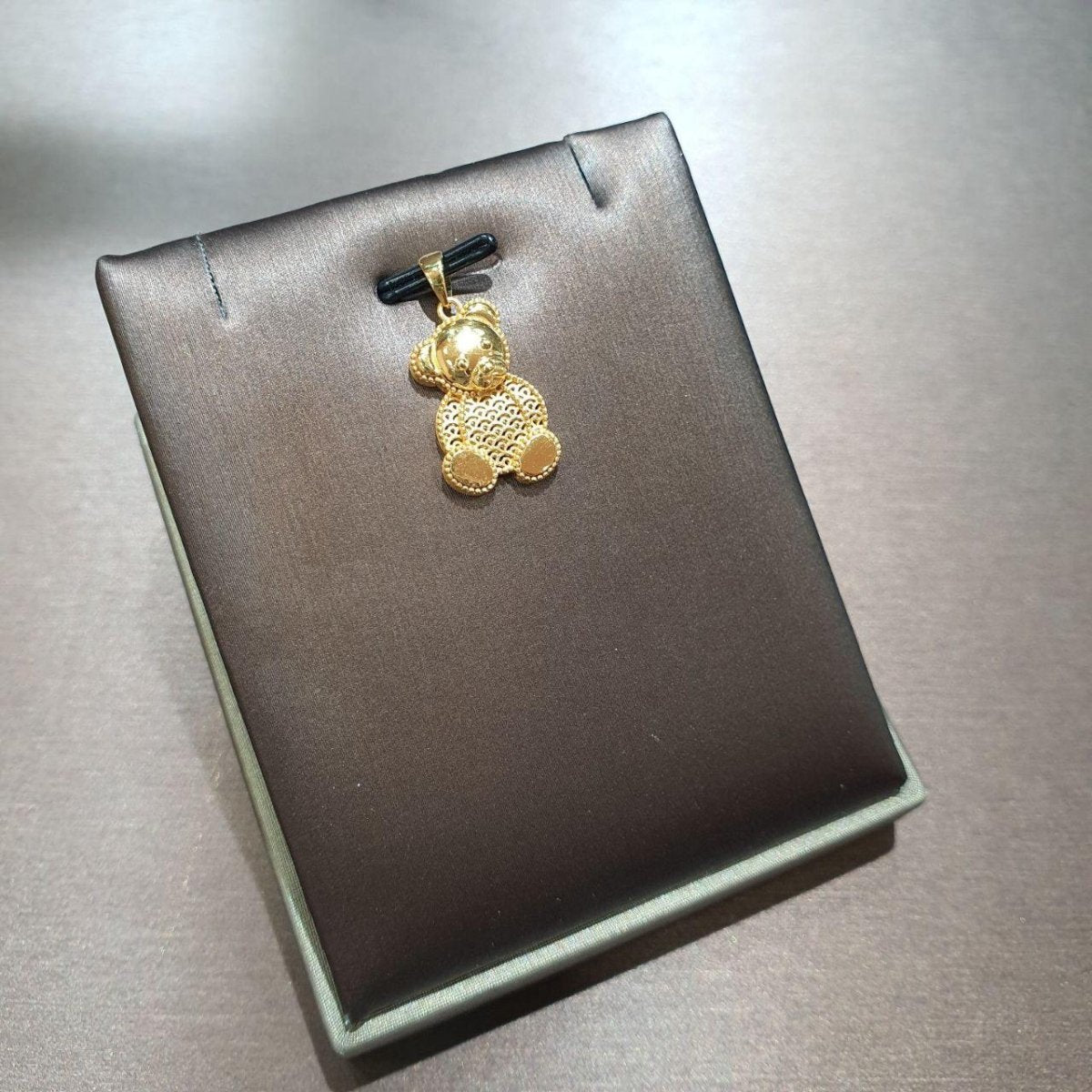 916 gold seated bear pendant with openwork body and polished paws on a grey display