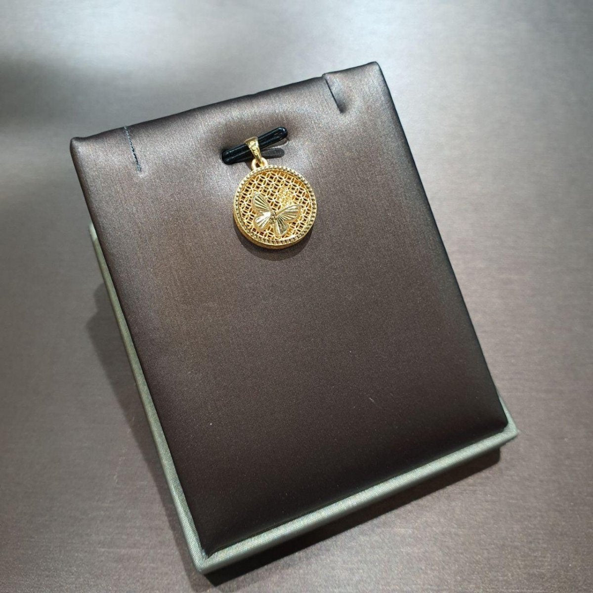 Round 916 gold openwork pendant with a butterfly motif on a grey display