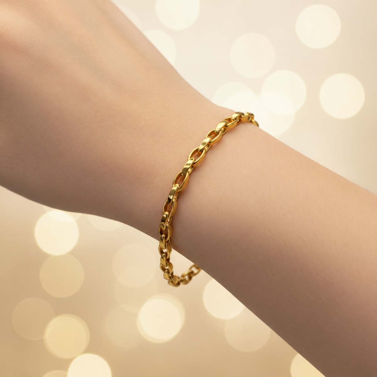 Guild Bullion 22K / 916 gold Oval Anchor Bracelet worn on a wrist against a warm bokeh background