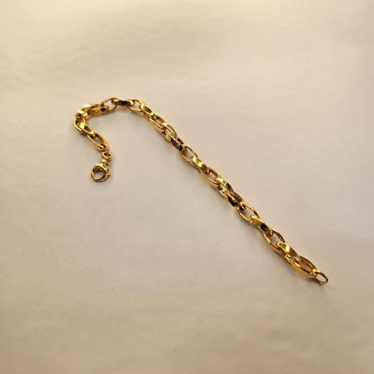Guild Bullion 22K / 916 gold Oval Anchor Bracelet showing polished oval links, lobster clasp and end ring on cream fabric