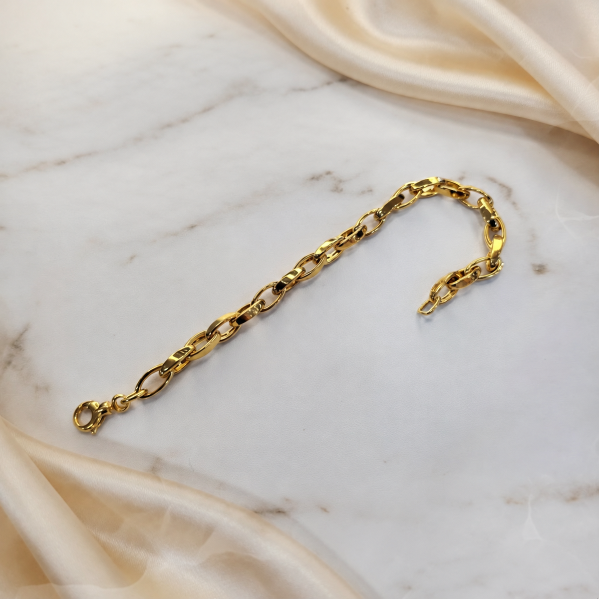 Guild Bullion 22K / 916 gold Oval Anchor Bracelet curved on white marble with lobster clasp visible at the lower left
