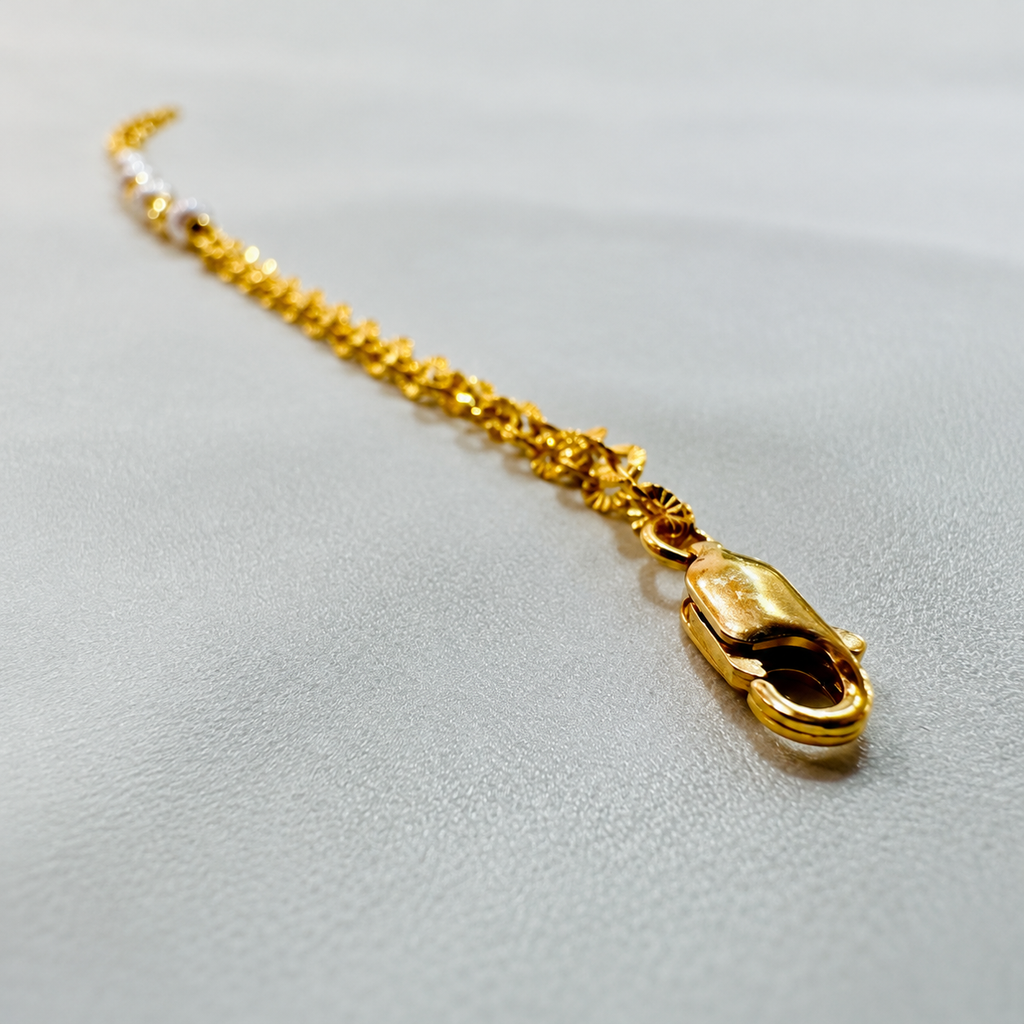 Guild Bullion 916 gold pearl-style bead bracelet close-up of lobster clasp and textured chain on pale grey fabric